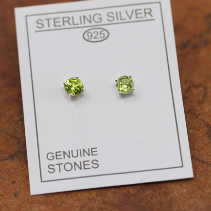 A pair of sterling silver peridot stud earrings displayed on a card with the text 'Sterling Silver' and 'Genuine Stones'.