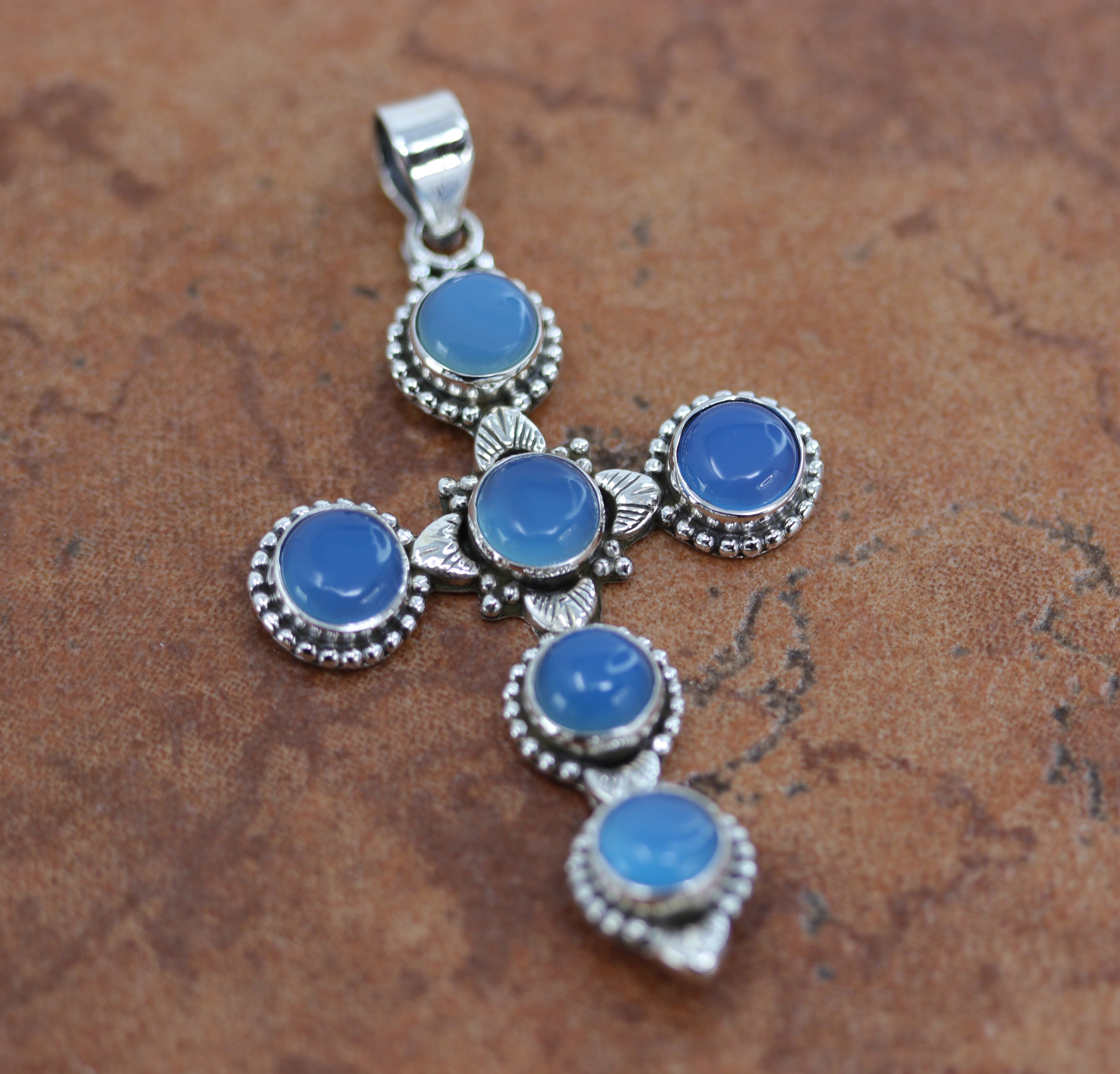 It is made from Sterling Silver and blue chalcedony. It is about 2 1/2" in length including the bail, and about 1 7/16" in width.