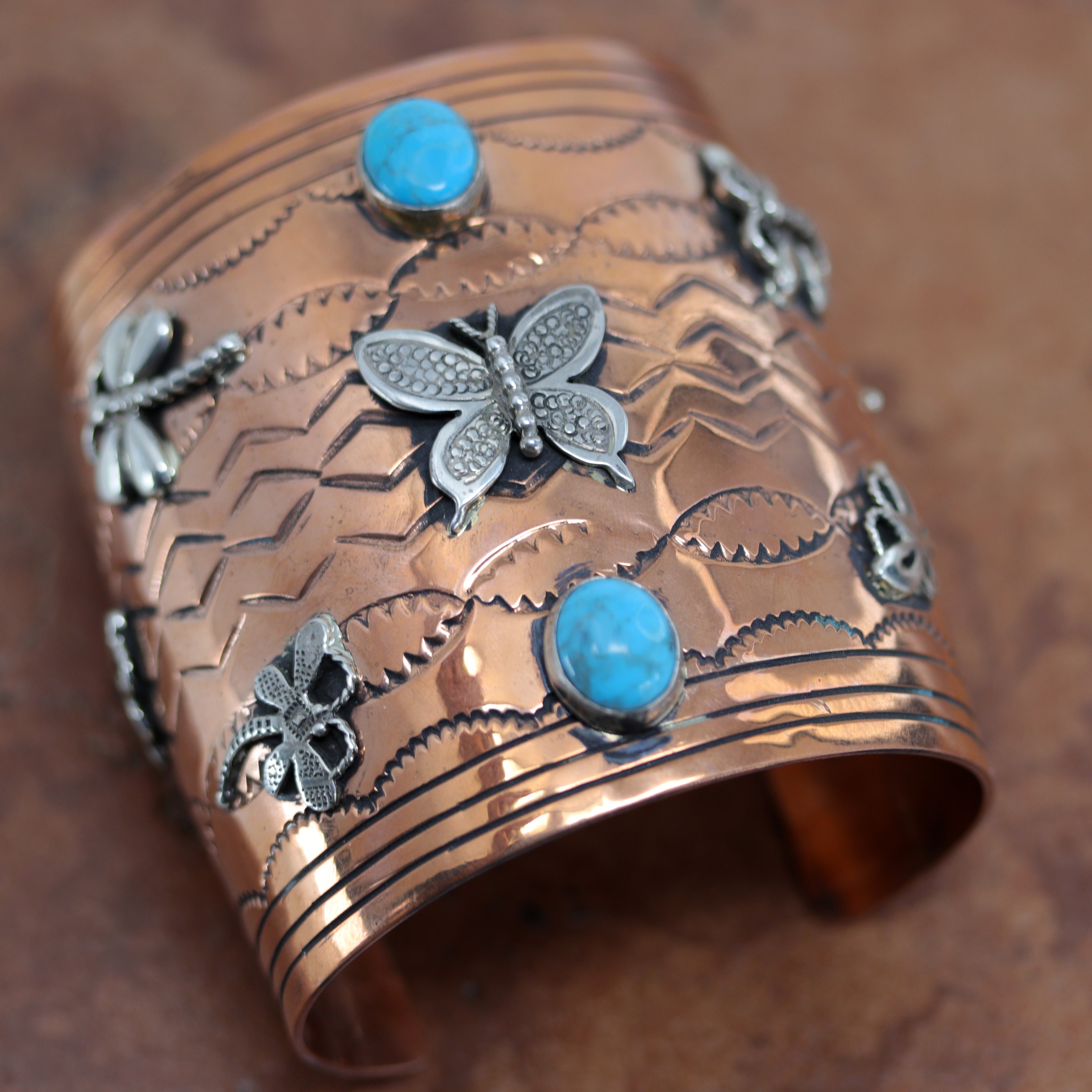 A beautiful Navajo Native American butterfly bracelet. It is made from copper, turquoise, and sterling silver. It is about 6 1/8" around and about 3" wide at the widest point. The opening is about 1 3/4".