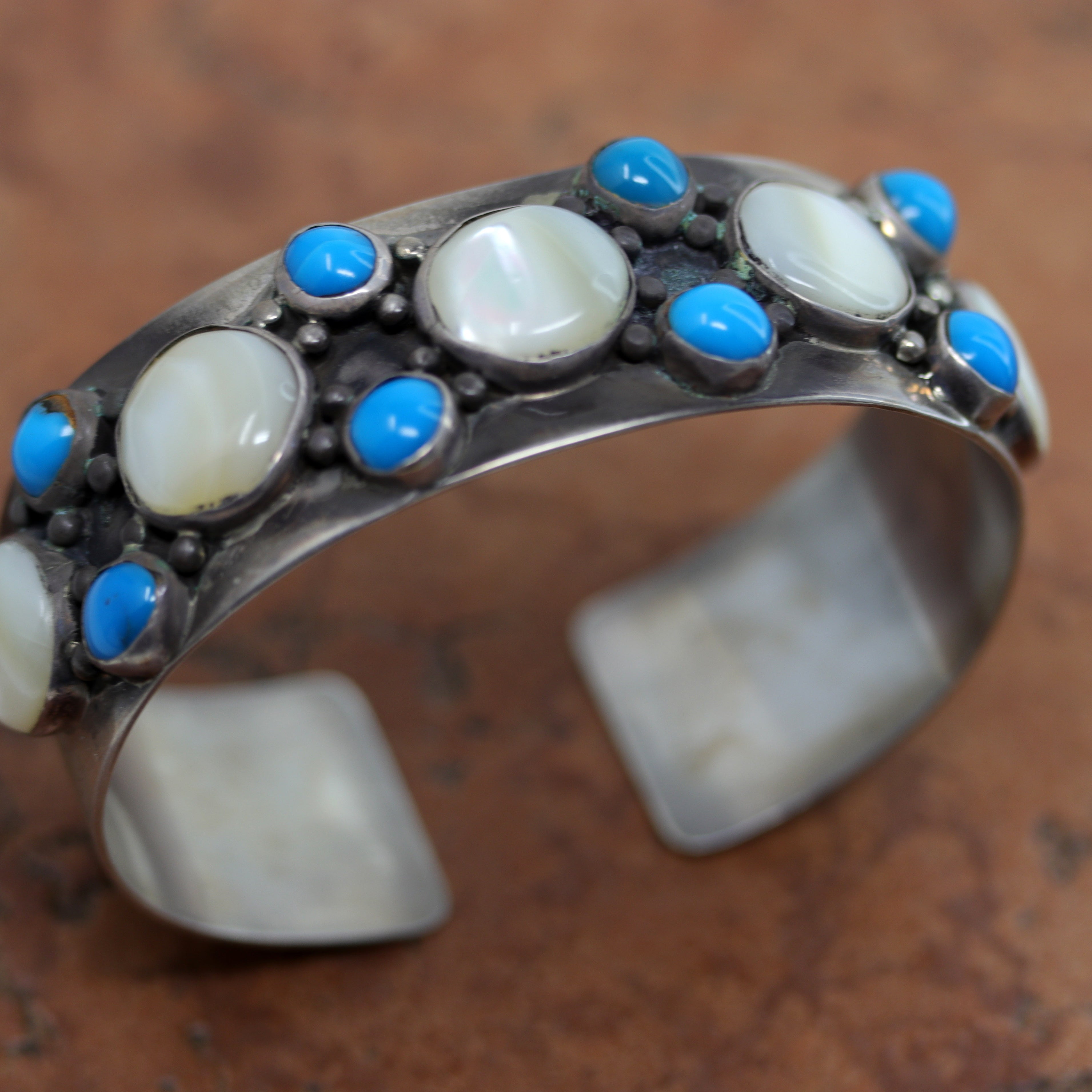 Navajo Native American bracelet by Nakai. This gorgeous cuff is made from sterling silver, mother of pearl, and turquoise. It is about 7 1/4" around and about 1 1/8" wide at the widest point. The opening is about 1", and partly flexible.