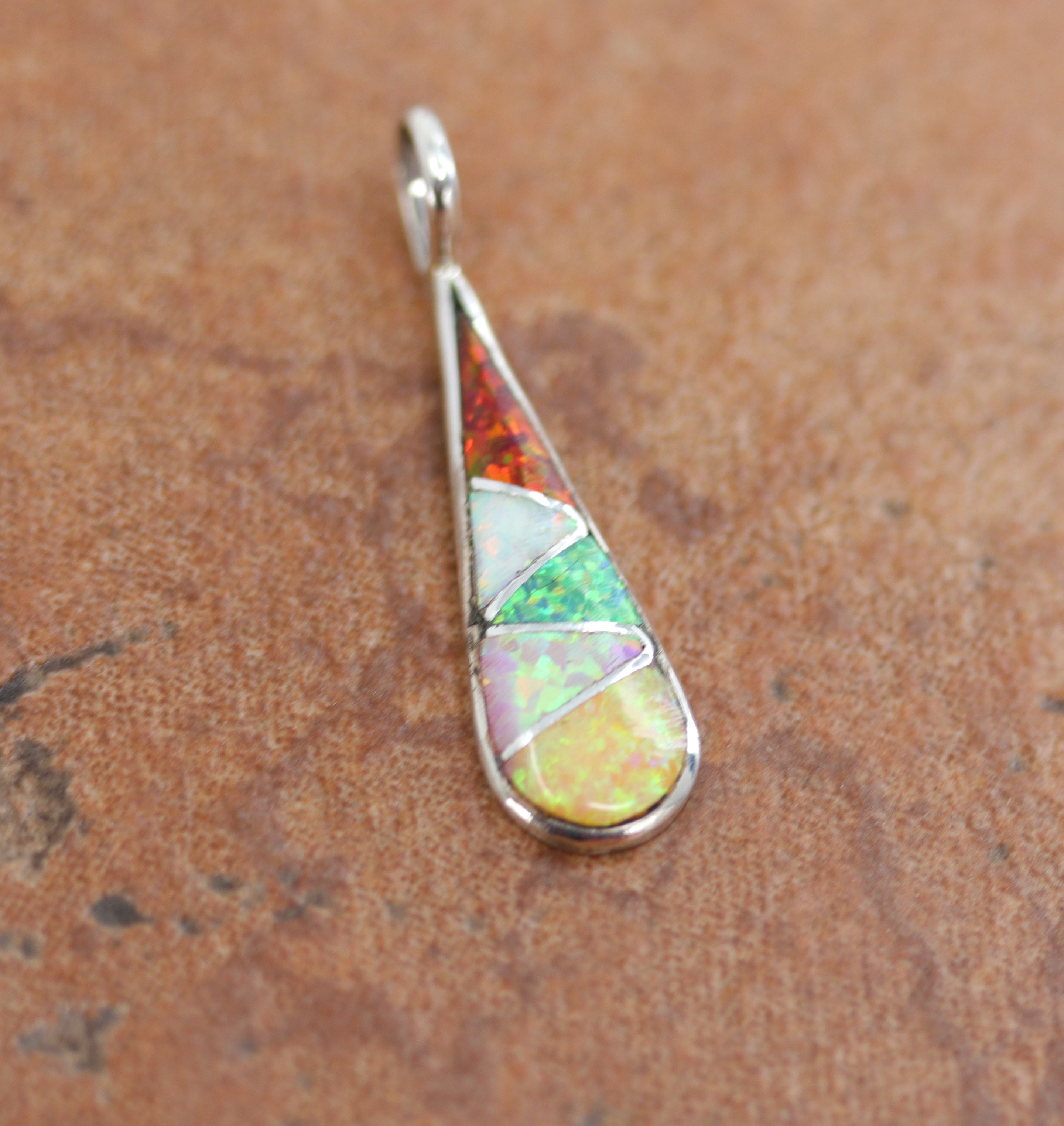 A beautiful pendant made from sterling silver and created opal. The pendant measures 1 1/4" by 3/8". 