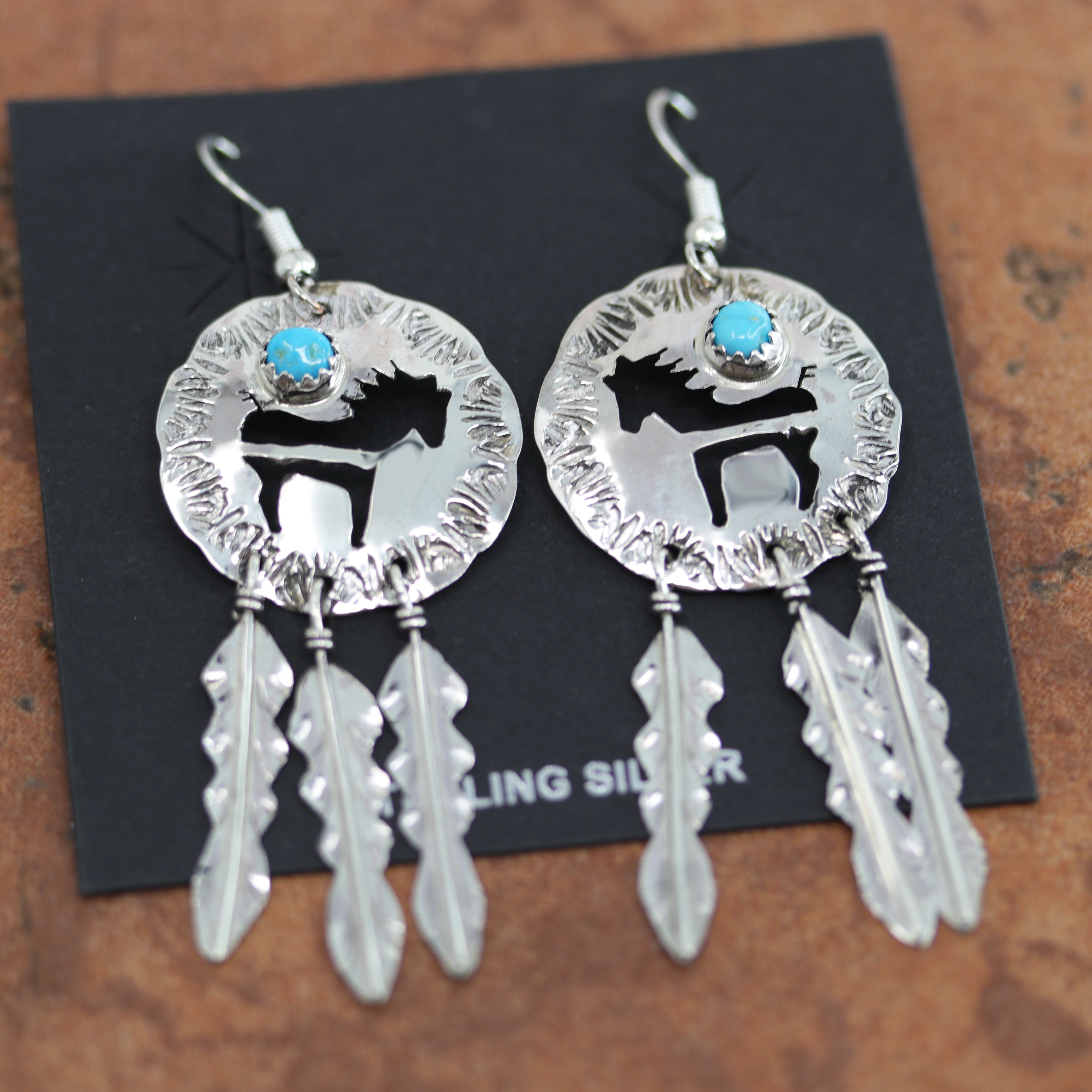 Navajo silver horse earrings. They are made from sterling silver and turquoise. Each earring is 2 5/8" in length including the hook and 1" in width.