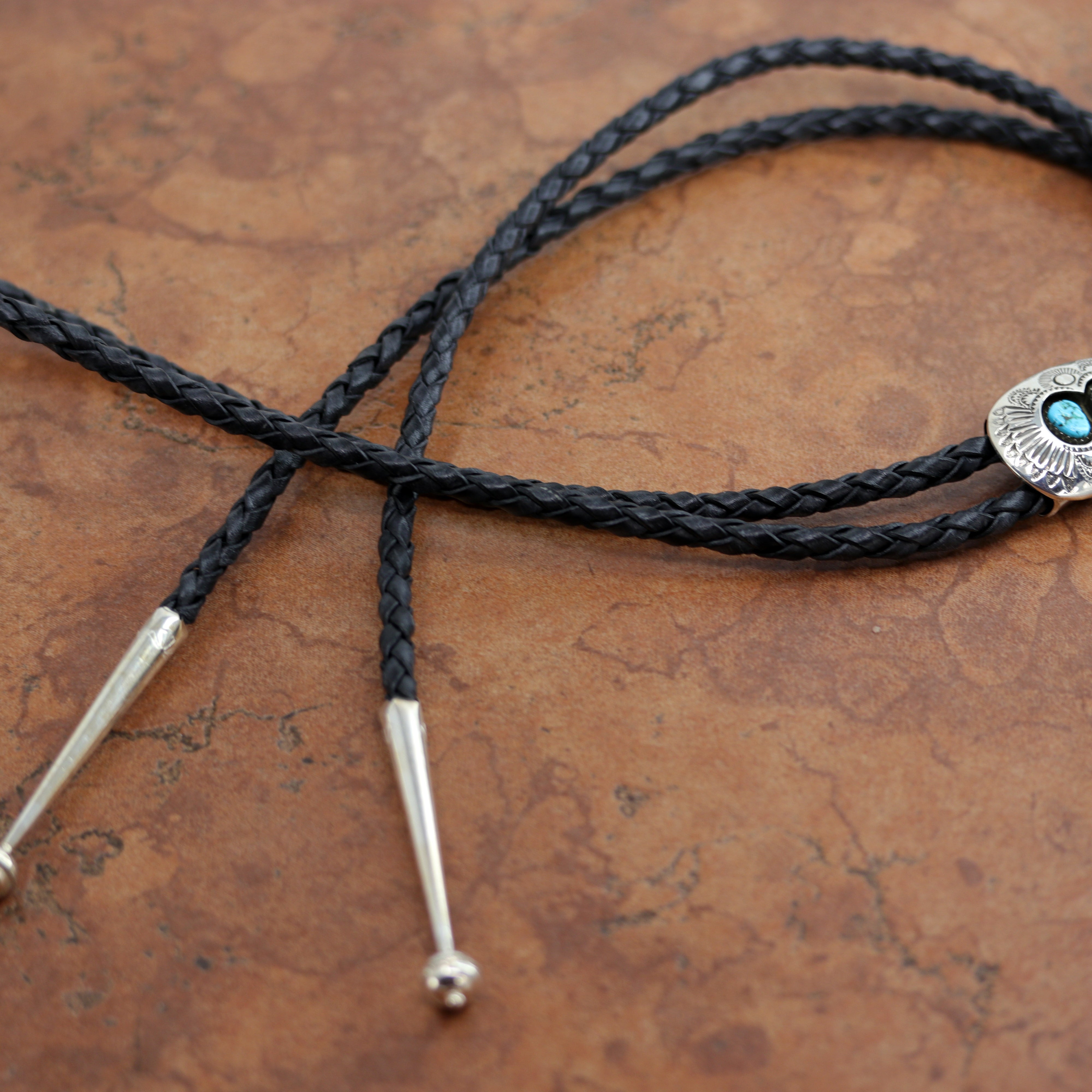 An authentic Navajo Native American Bolo Tie. The bolo tie is made of sterling silver and turquoise. The cord measures about 44". The bolo measures 1 1/2" by 1".