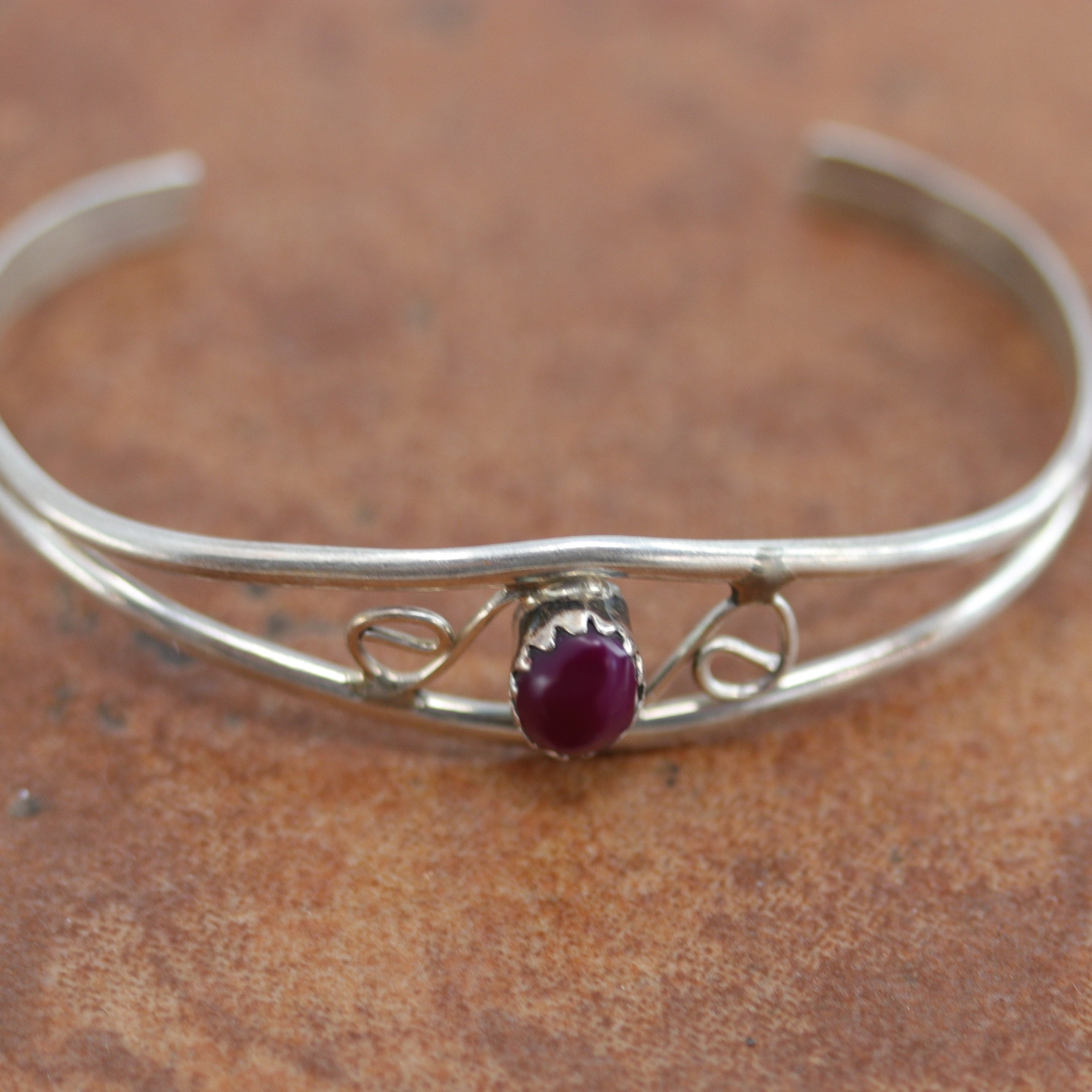 Navajo Native American childrens bracelet. It is made from sterling silver and sugilite. It is about 3 3/8" around and about 3/8" wide at the widest point. The opening is about 3/4", and partly flexible.