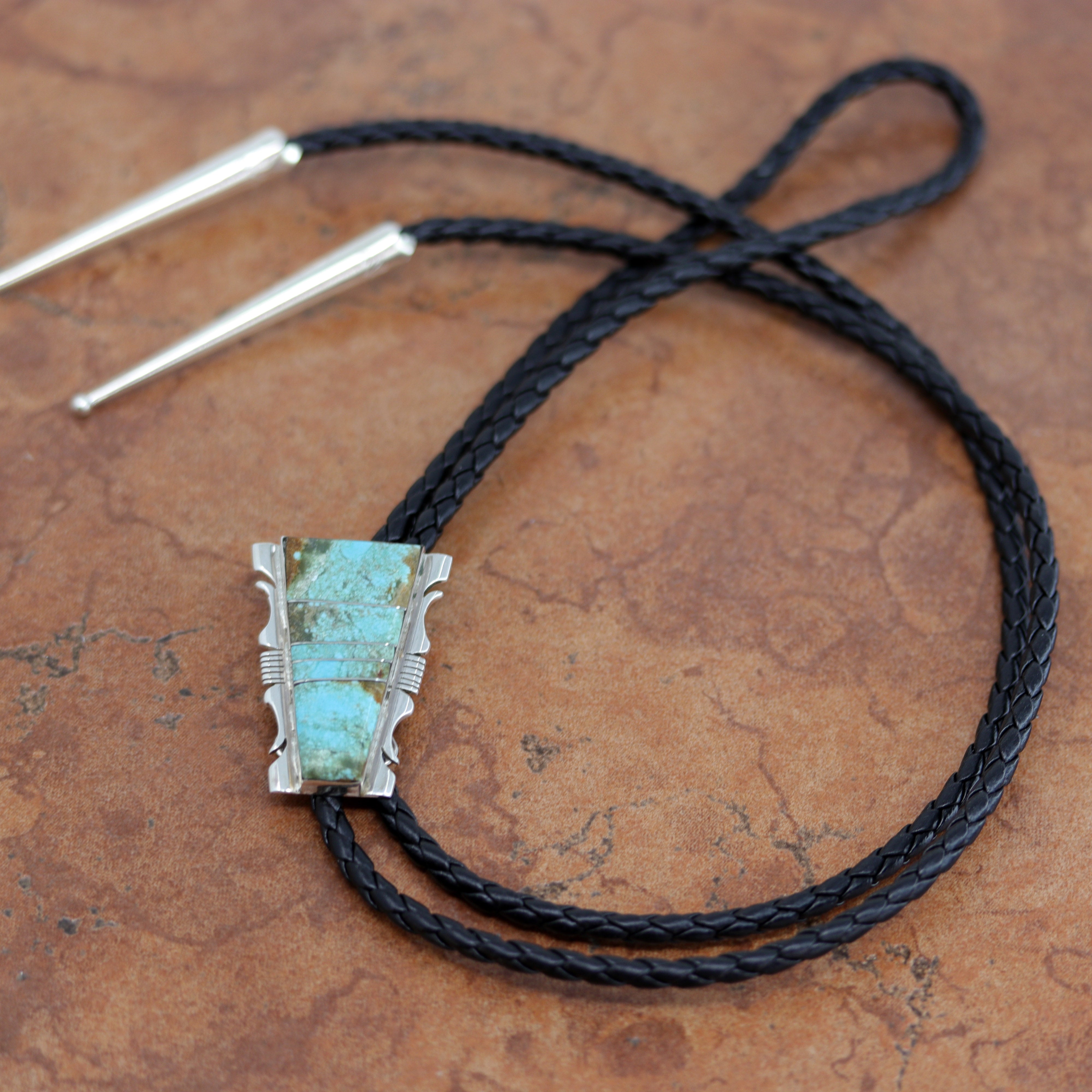 Navajo Native American Bolo Tie. The bolo tie is made of sterling silver and turquoise. The cord is about 44". The bolo measures 1 1/8" by 1 1/8".