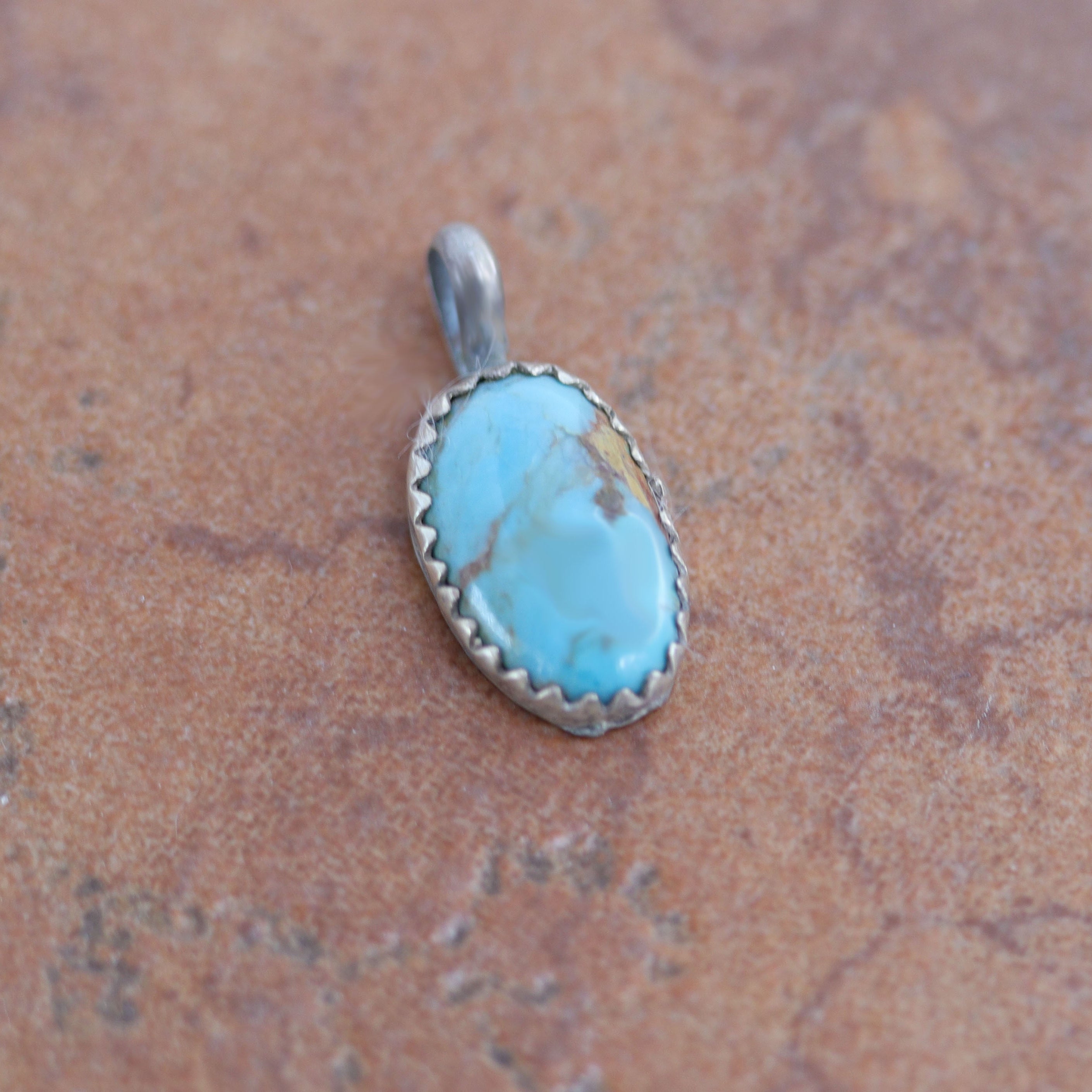 A beautiful Navajo Native American Pendant. It is made from sterling silver and turquoise. It is 3/8" in width and 3/4" in length including the bail.