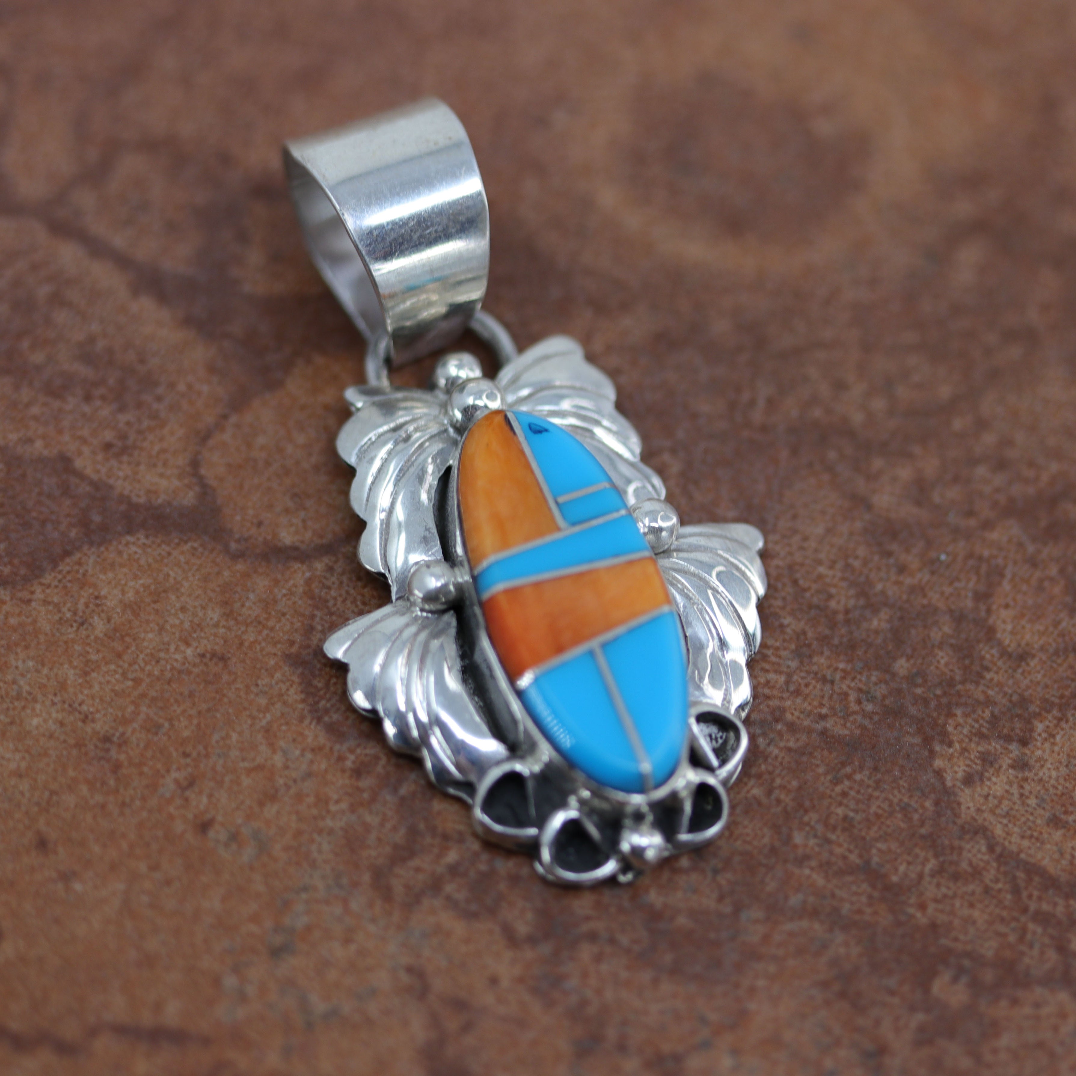 A beautiful Navajo Native American Pendant. It is made from sterling silver and multi-stone inlay. It is 2" long and about 1 1/8" wide. 