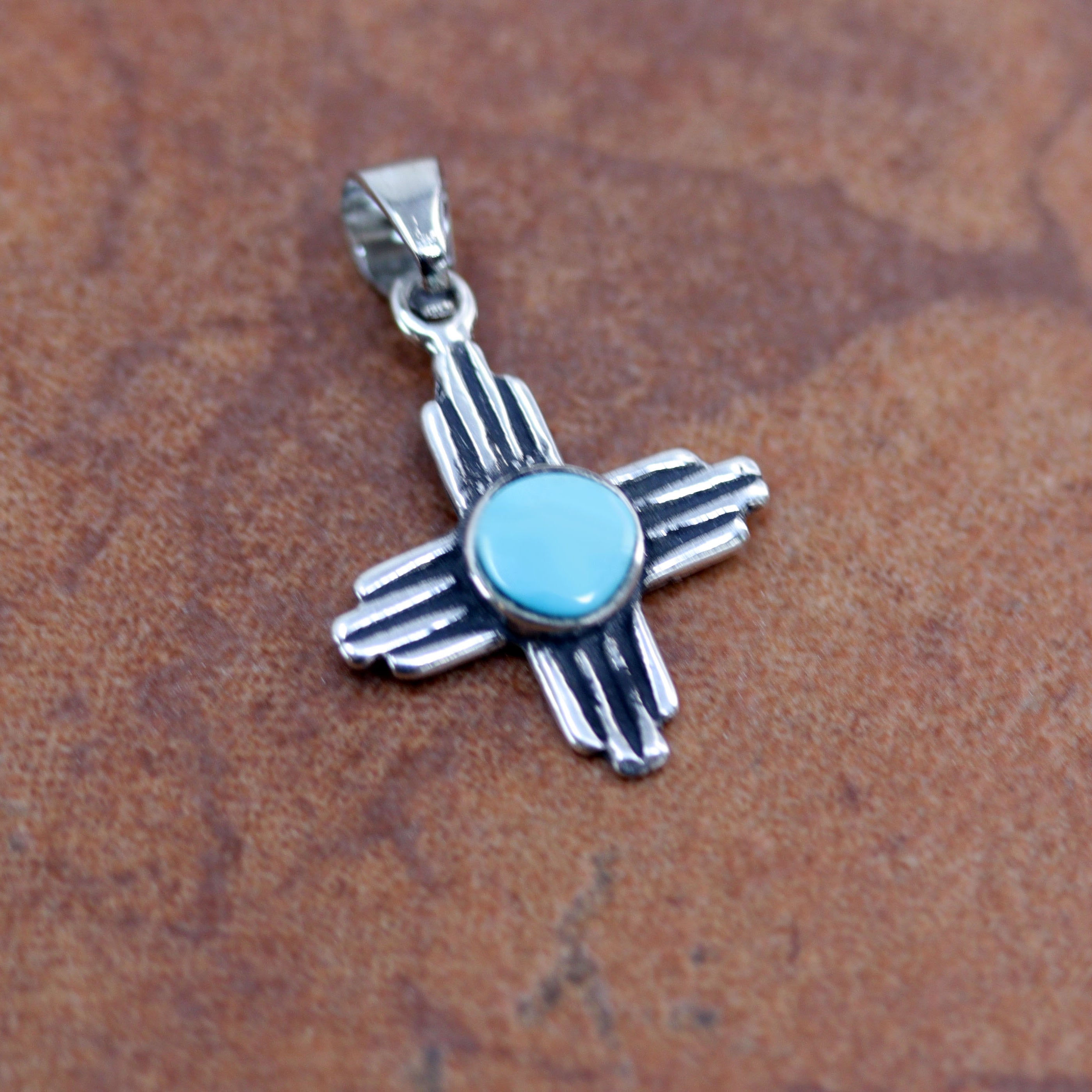 It is made from sterling silver and turquoise. It is 1" long, and about 3/4" wide.