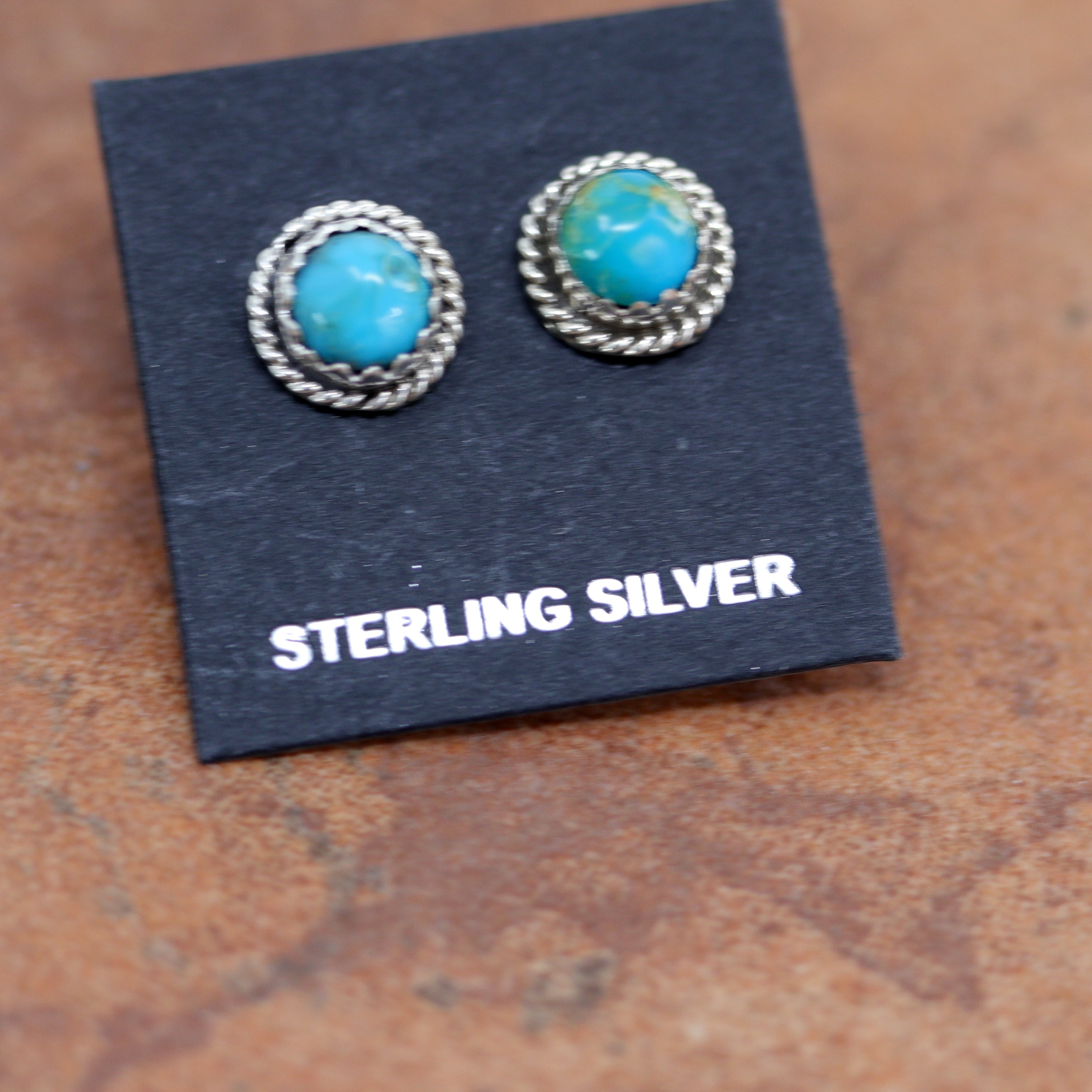 Circular silver stud earrings with round turquoise stones in the middle